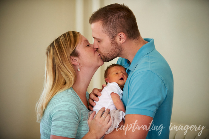 mom and dad kissing and embracing baby
