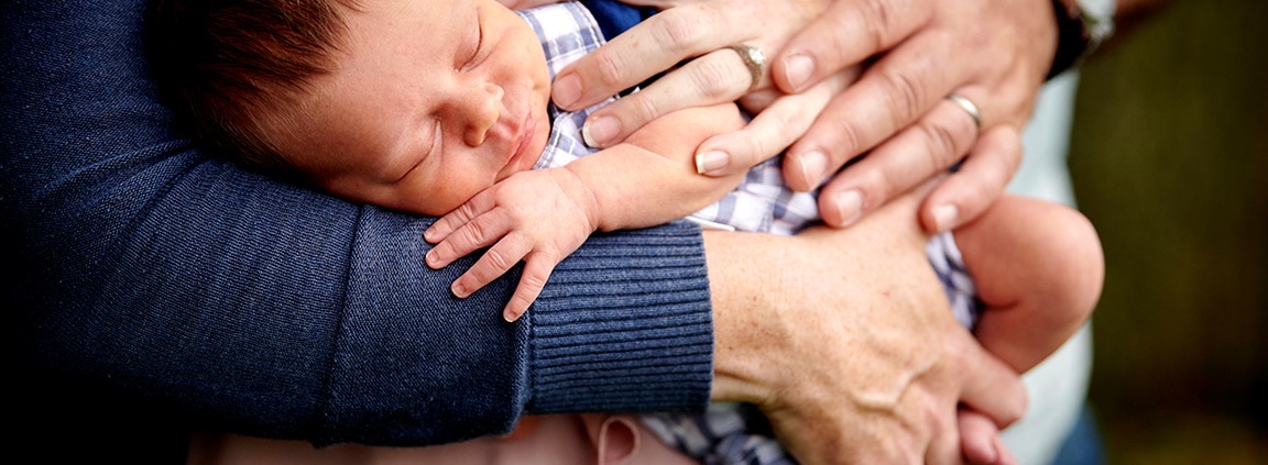 closeup of sleeping baby with parents' hands