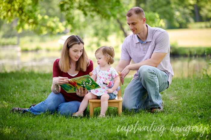 young family reading a book to their daughter