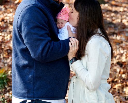 parents hold baby with kiss