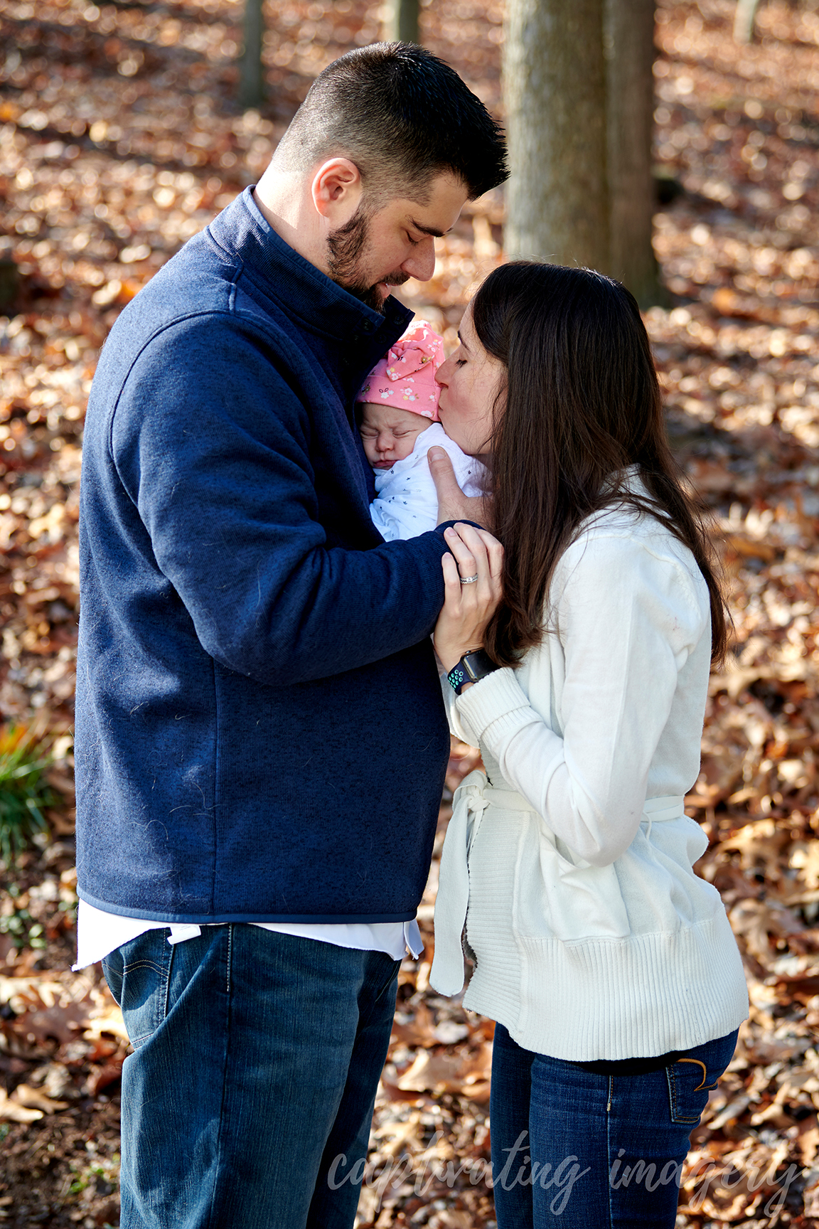 parents hold baby with kiss