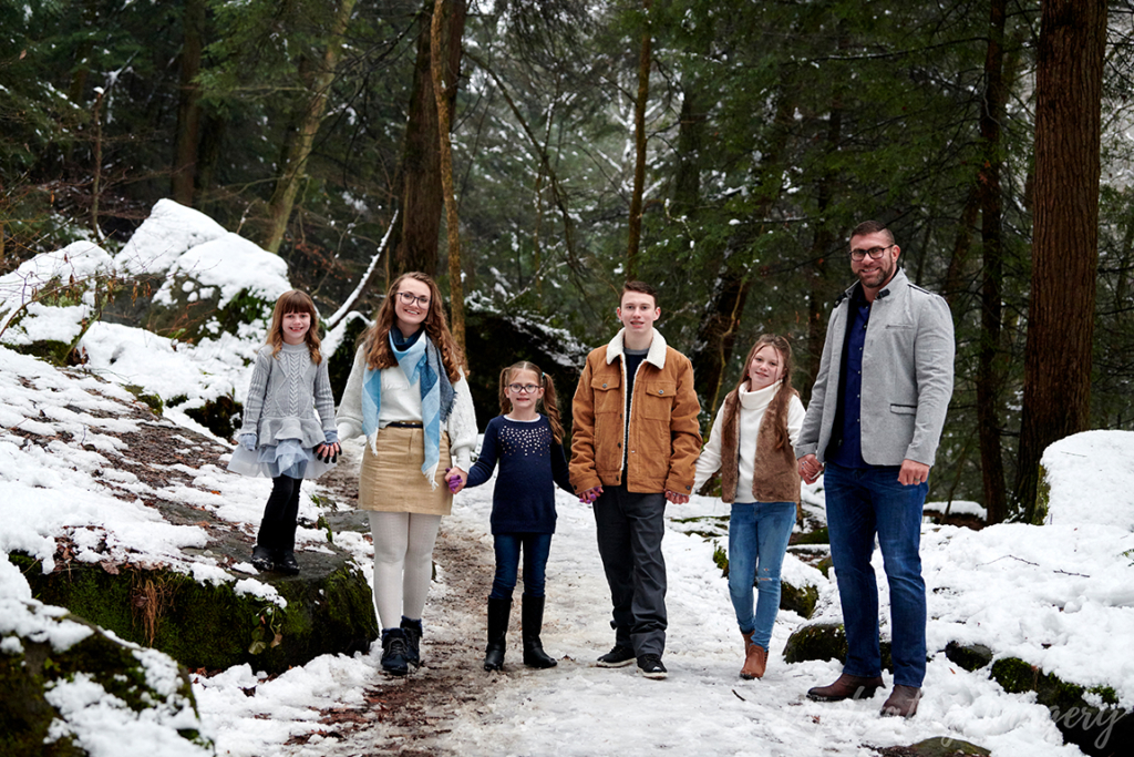 family holding hands on snowy hiking trail