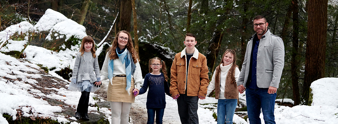 family holding hands on snowy hiking trail