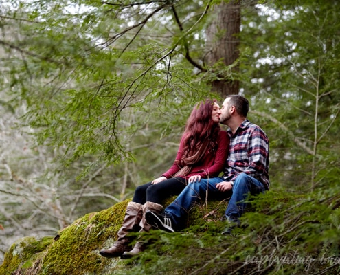 couple kisses on mossy rock