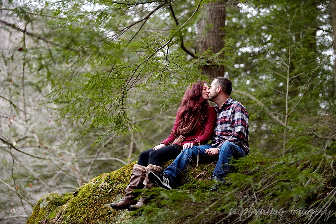 couple kisses on mossy rock