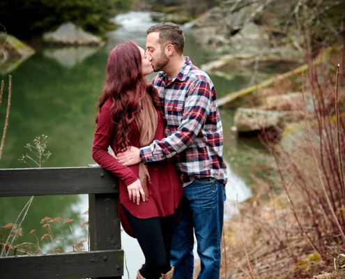 couple kisses by creek