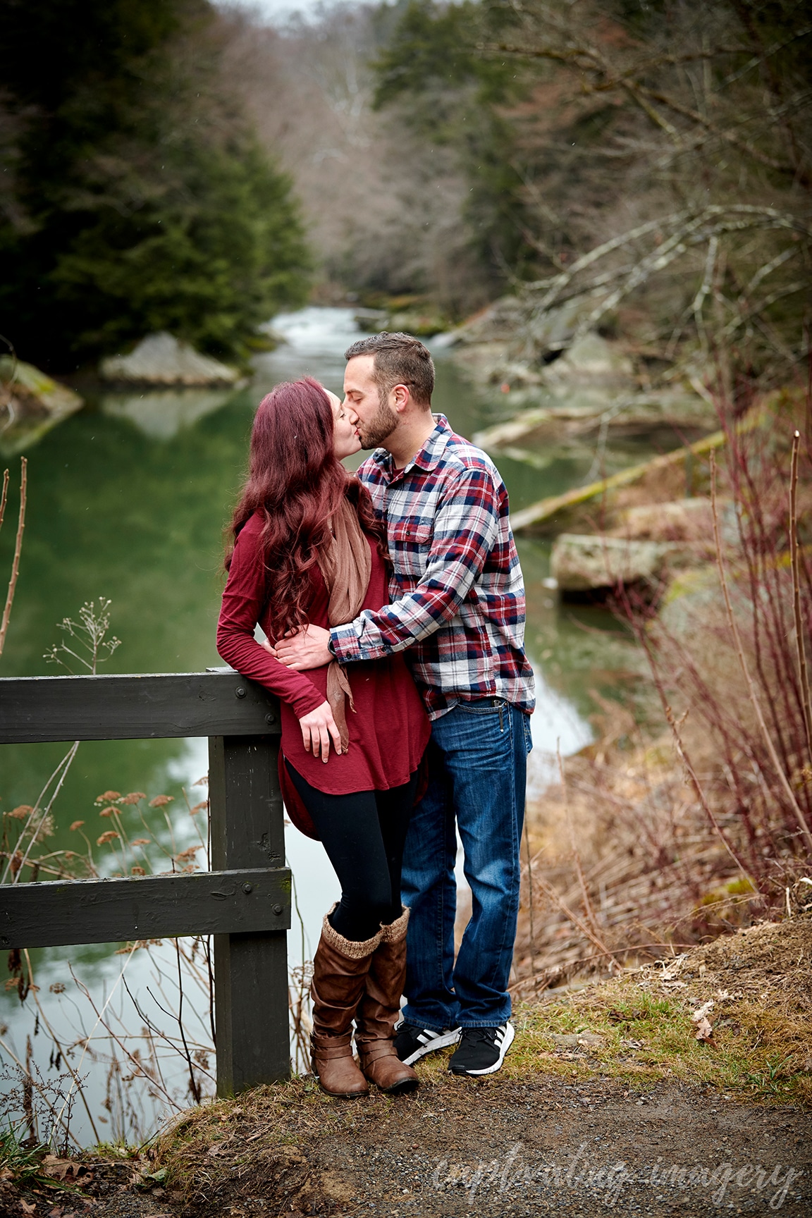 couple kisses by creek