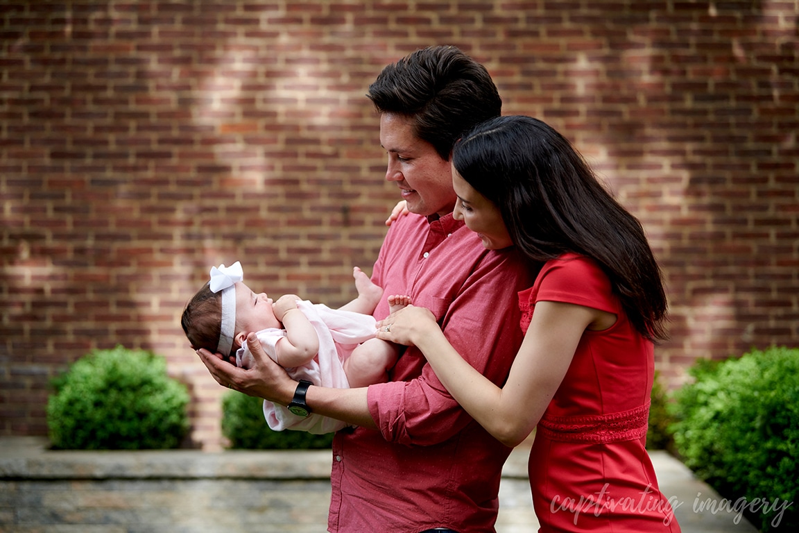 dad holds baby while mom looks on