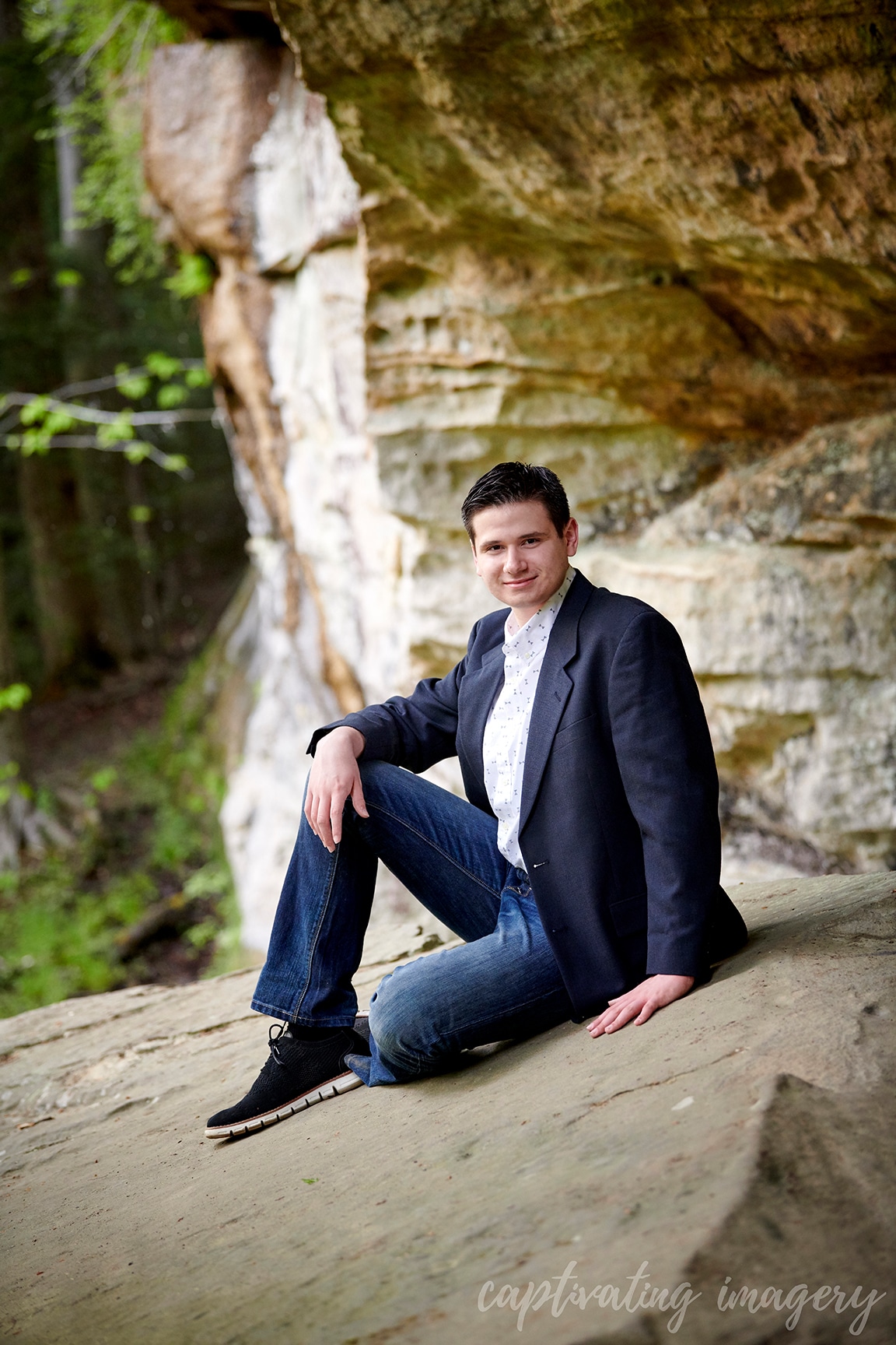 boy in suit jacket sitting under rock formation