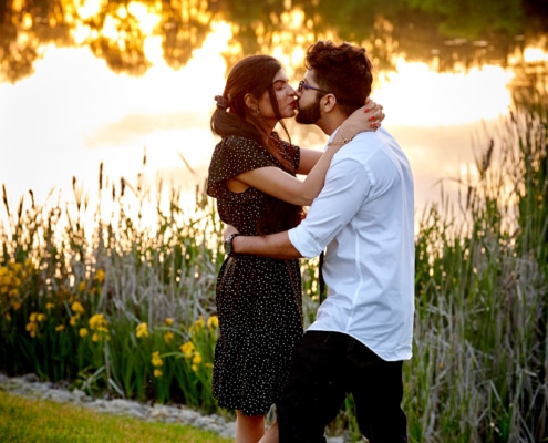 couple kiss by pond at sunset