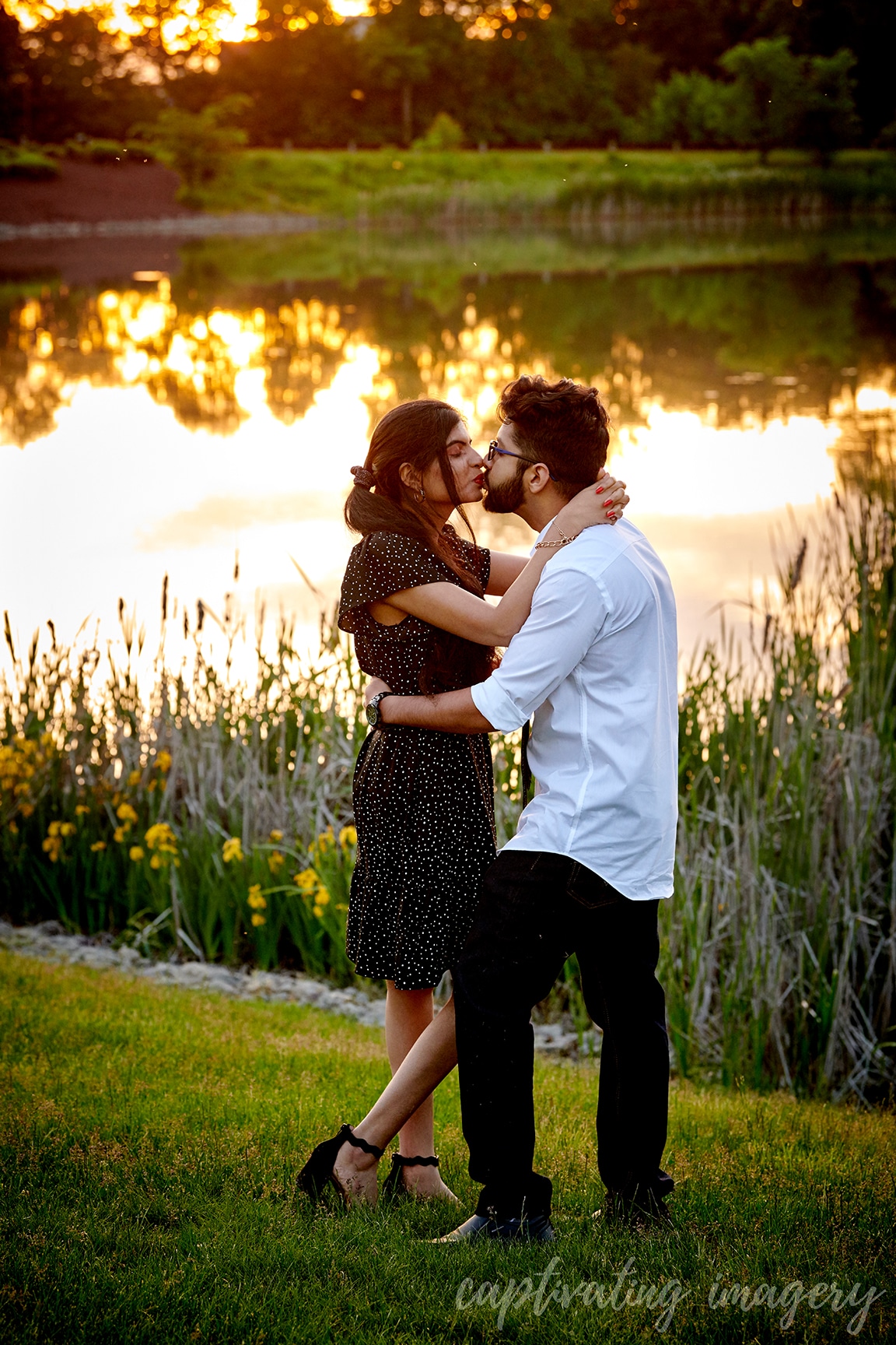 couple kiss by pond at sunset