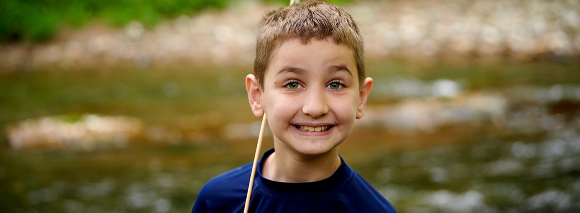 boy smiling with creek in background