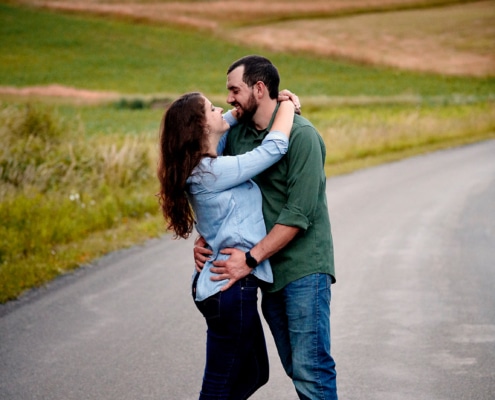 couple embraces in front of sunset