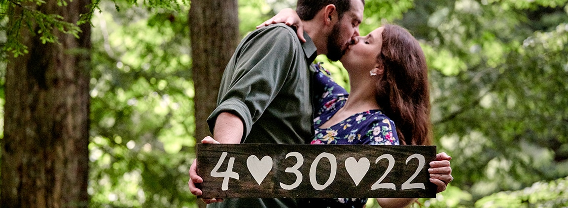 couple kissing while holding sign with wedding date