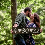 couple kissing while holding sign with wedding date