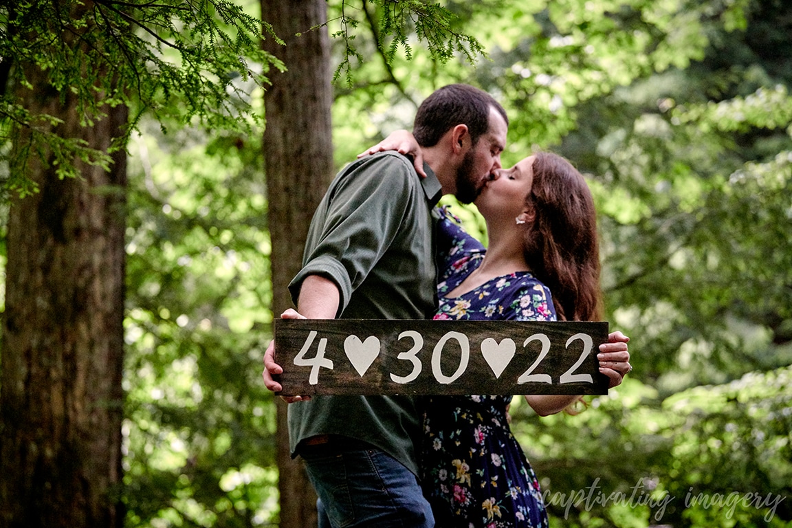 couple kissing while holding sign with wedding date