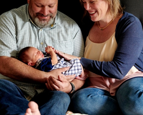 dad holds newborn with mom on bed