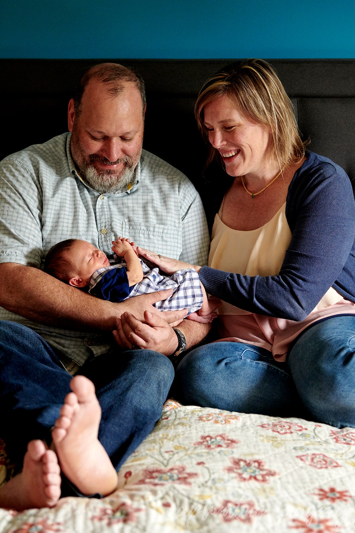 dad holds newborn with mom on bed