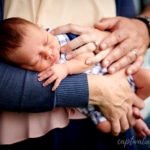 closeup of sleeping baby with parents' hands