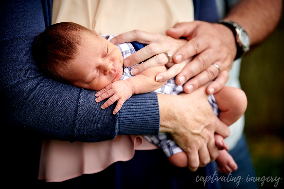 closeup of sleeping baby with parents' hands